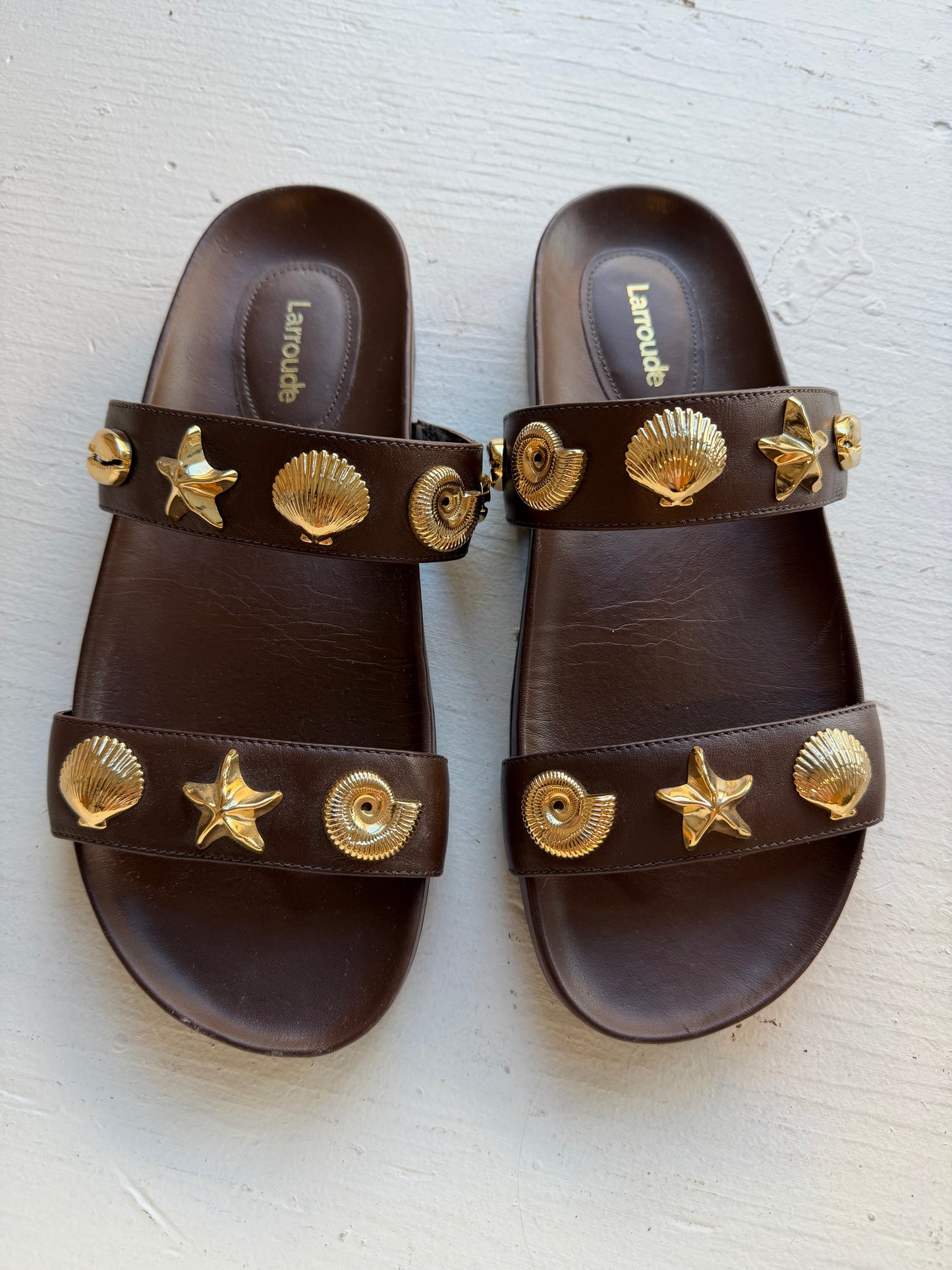 Larroude Madison Slide Sandals in brown leather, featuring gold-toned starfish and seashell hardware. Size 9