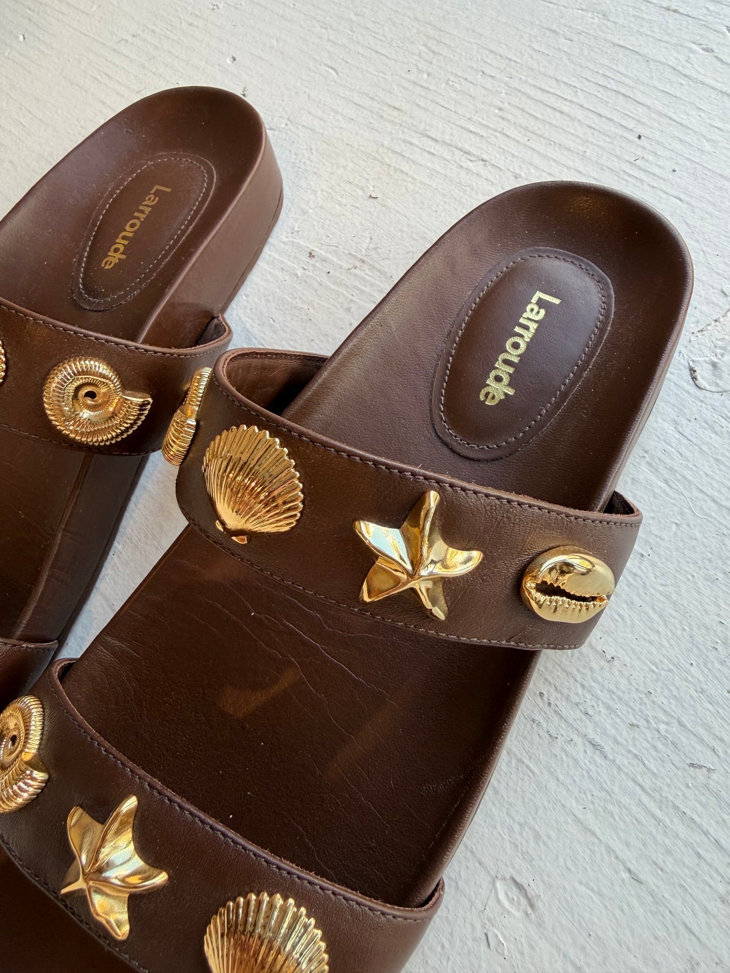 Larroude Madison Slide Sandals in brown leather, featuring gold-toned starfish and seashell hardware. Size 9