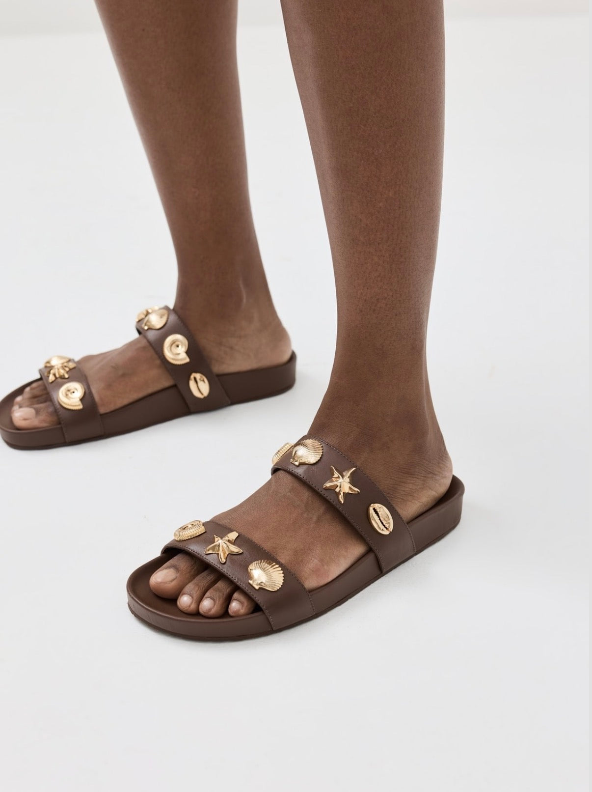Larroude Madison Slide Sandals in brown leather, featuring gold-toned starfish and seashell hardware. Size 9